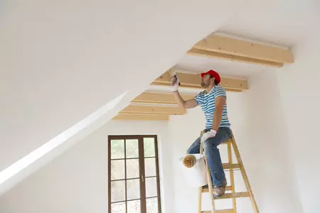 Homme qui peint le plafond sur une échelle
