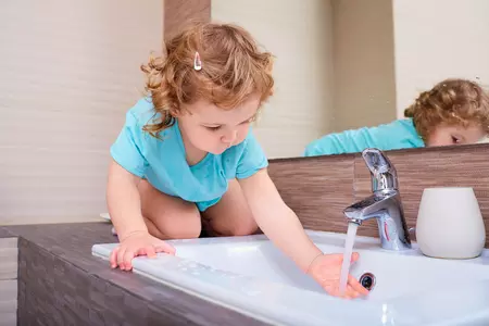 enfant mettant sa main sous l'eau